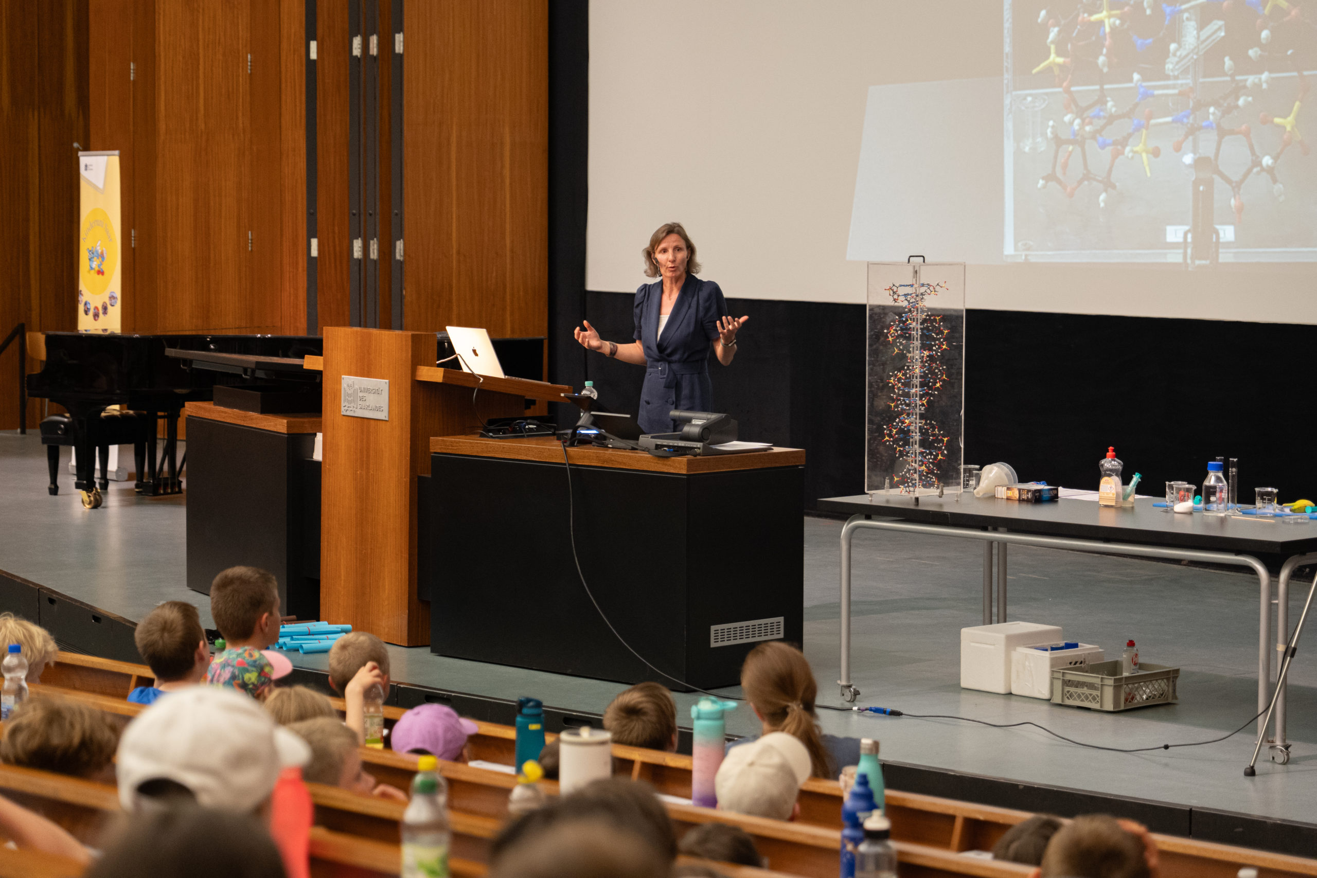Sur la photo, on voit Julia Schulze-Hentrich, responsable de programme, donnant une conférence devant des enfants dans un auditorium.
